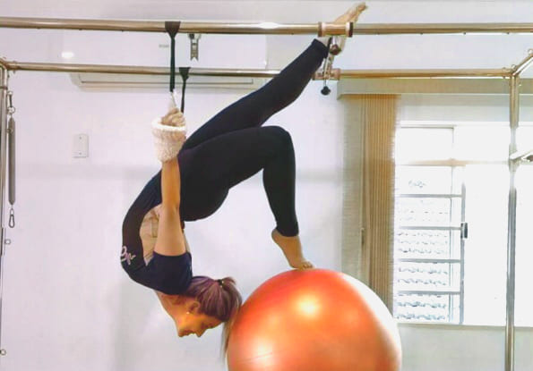 mulher fazendo posição de pilates com bola 