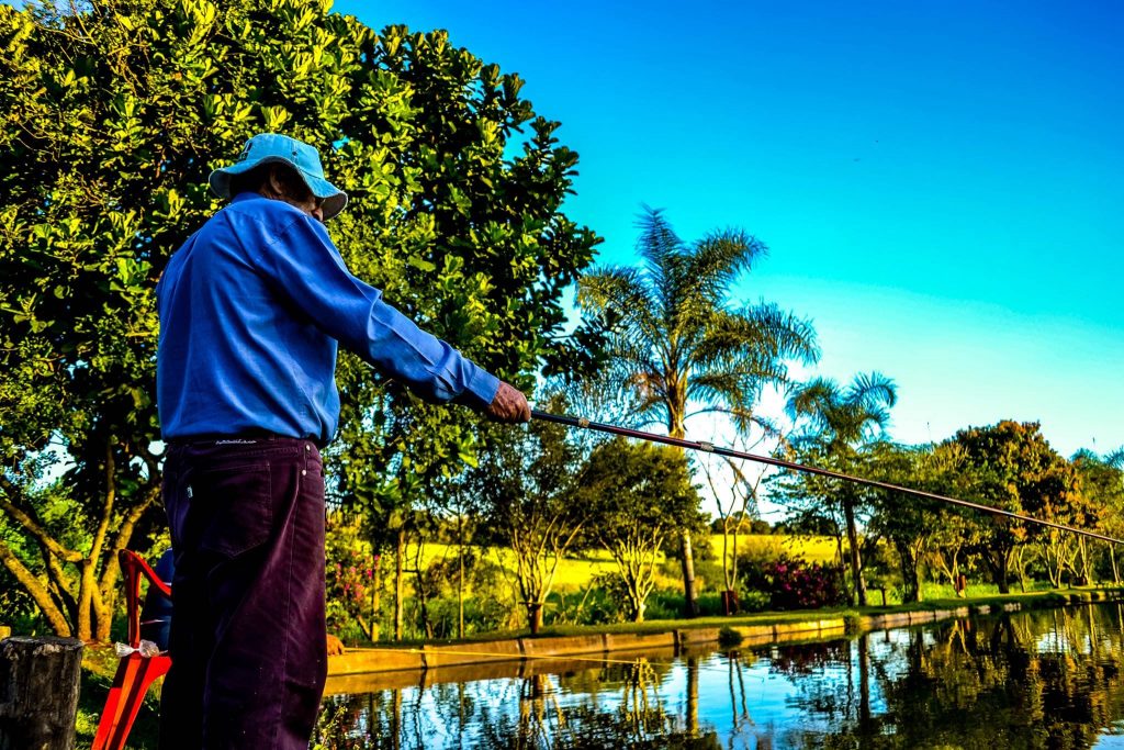 Homem em pé em frente a um lago pescando