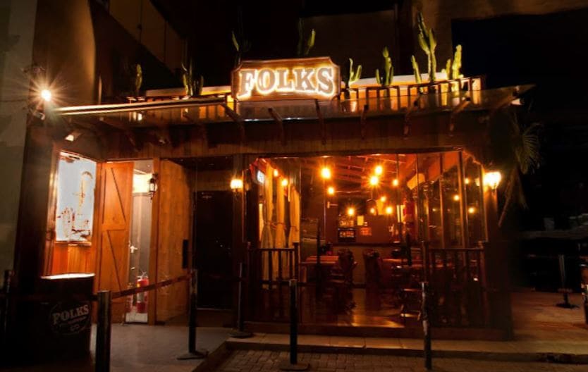 fachada do folks pub em madeira com meia iluminação