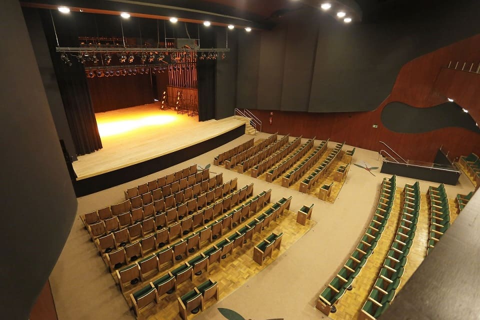 Interior do Cine Teatro Ouro Verde revitalizado com poltronas verdes e vista para o palco