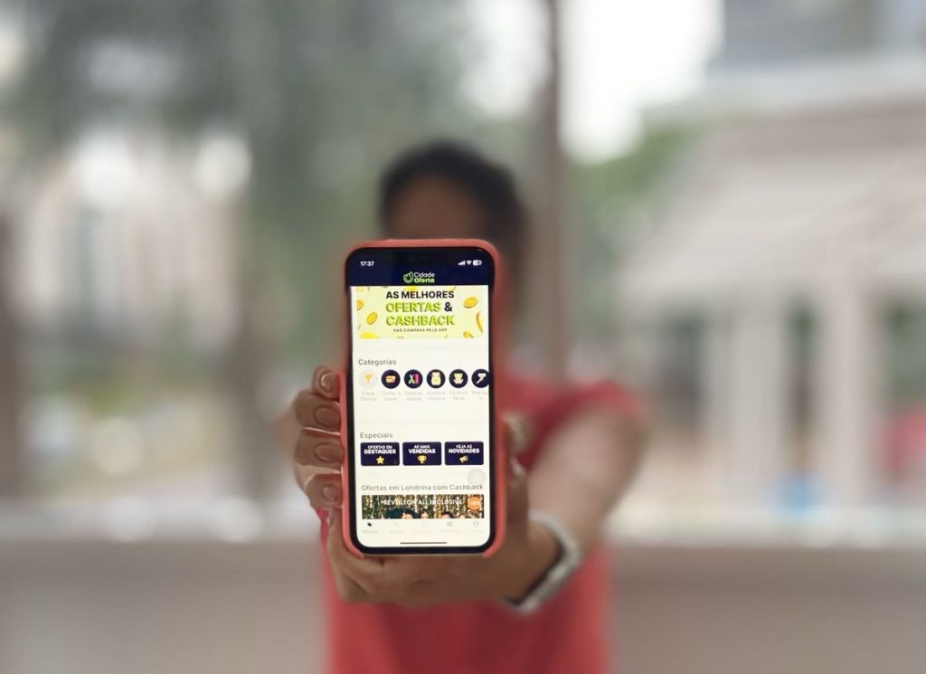Pessoa segurando smartphone exibindo ofertas e cashback, destacando as melhores promoções disponíveis para os usuários.